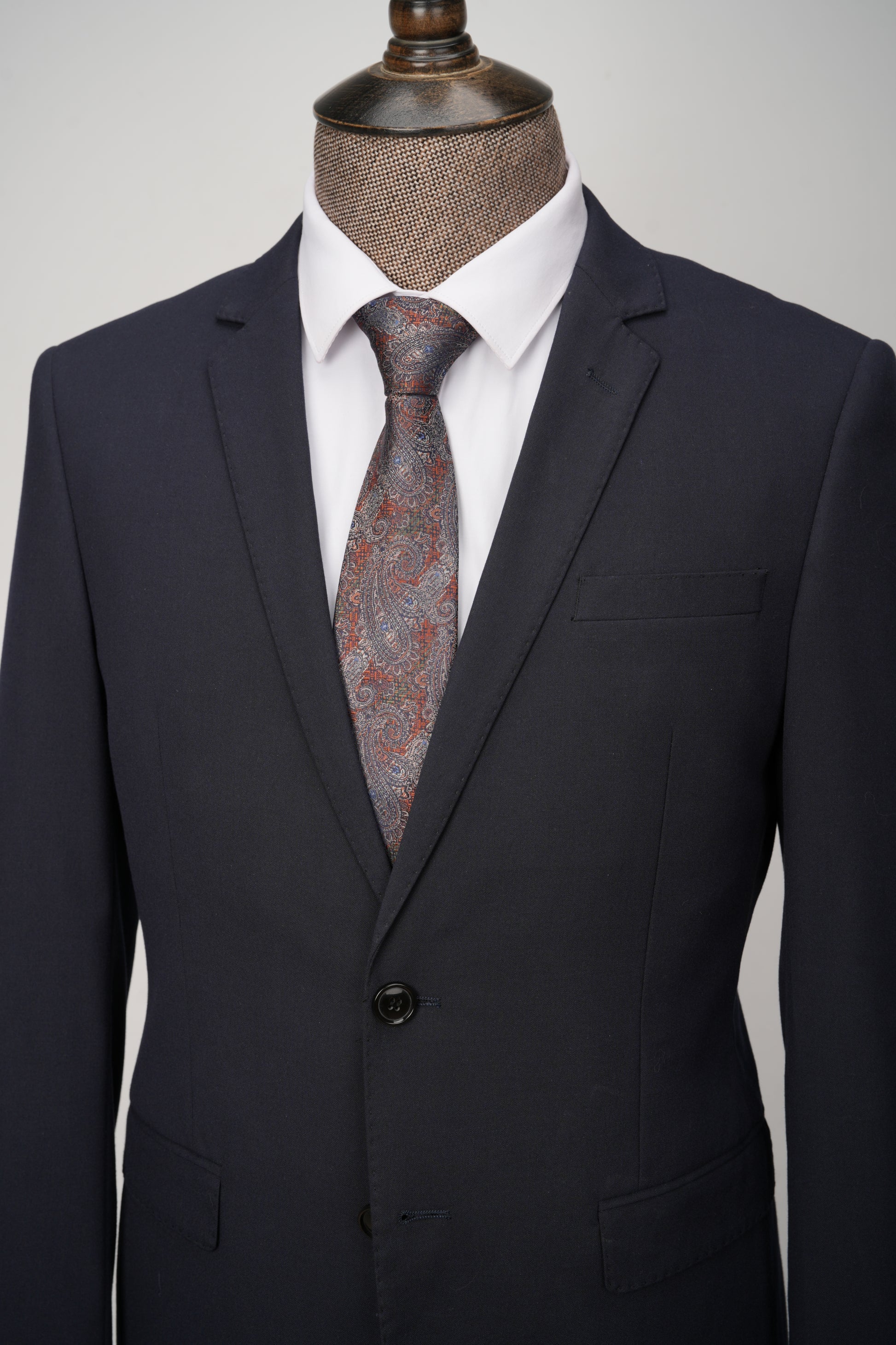 Navy suit jacket with a patterned tie on a mannequin against a neutral background
