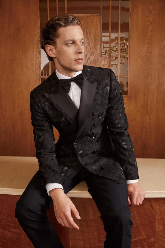 Embroidered black double breasted wedding tuxedo with peak lapels. Peak lapel tuxedo with black satin accents. Solid black pants with black satin stripe down the side. Black wedding tuxedo. Wedding tux for groom. Groom black wedding tuxedo.