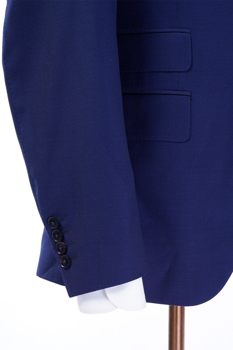 Blue wedding suit with peak lapel, a double breasted grey vest and grey pants. Blue and grey wedding suit. Blue wedding suit for groom. Grey wedding suit for groom. Blue suit with ticket pocket. Double breasted vest with shawl lapel.