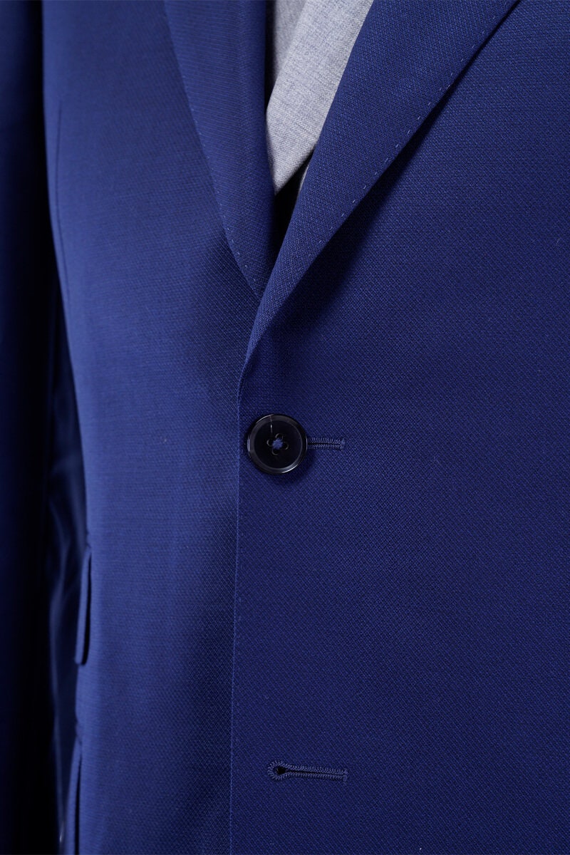 Blue wedding suit with peak lapel, a double breasted grey vest and grey pants. Blue and grey wedding suit. Blue wedding suit for groom. Grey wedding suit for groom. Blue suit with ticket pocket. Double breasted vest with shawl lapel.
