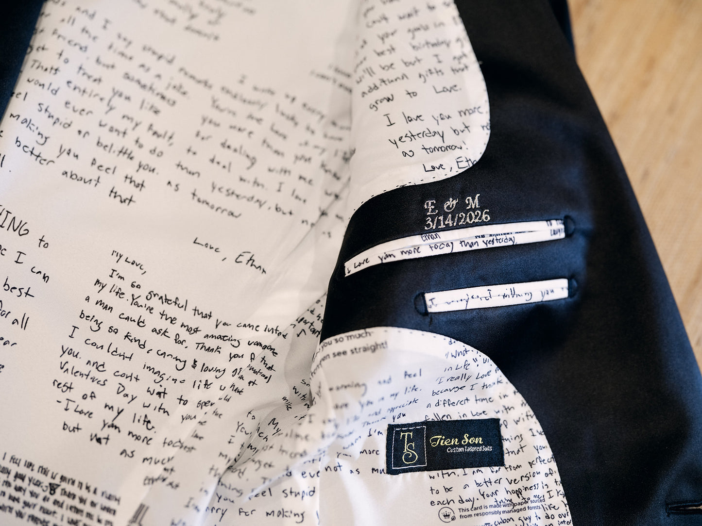 Navy suit jacket with handwritten notes and a label on a wooden surface