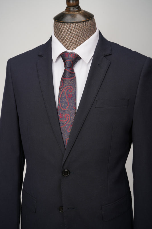 Black suit with a red paisley tie on a mannequin against a gray background