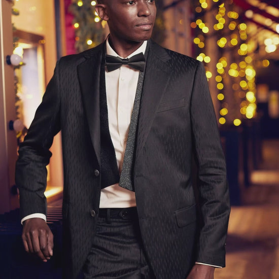 man wearing a formal black tux on a city street