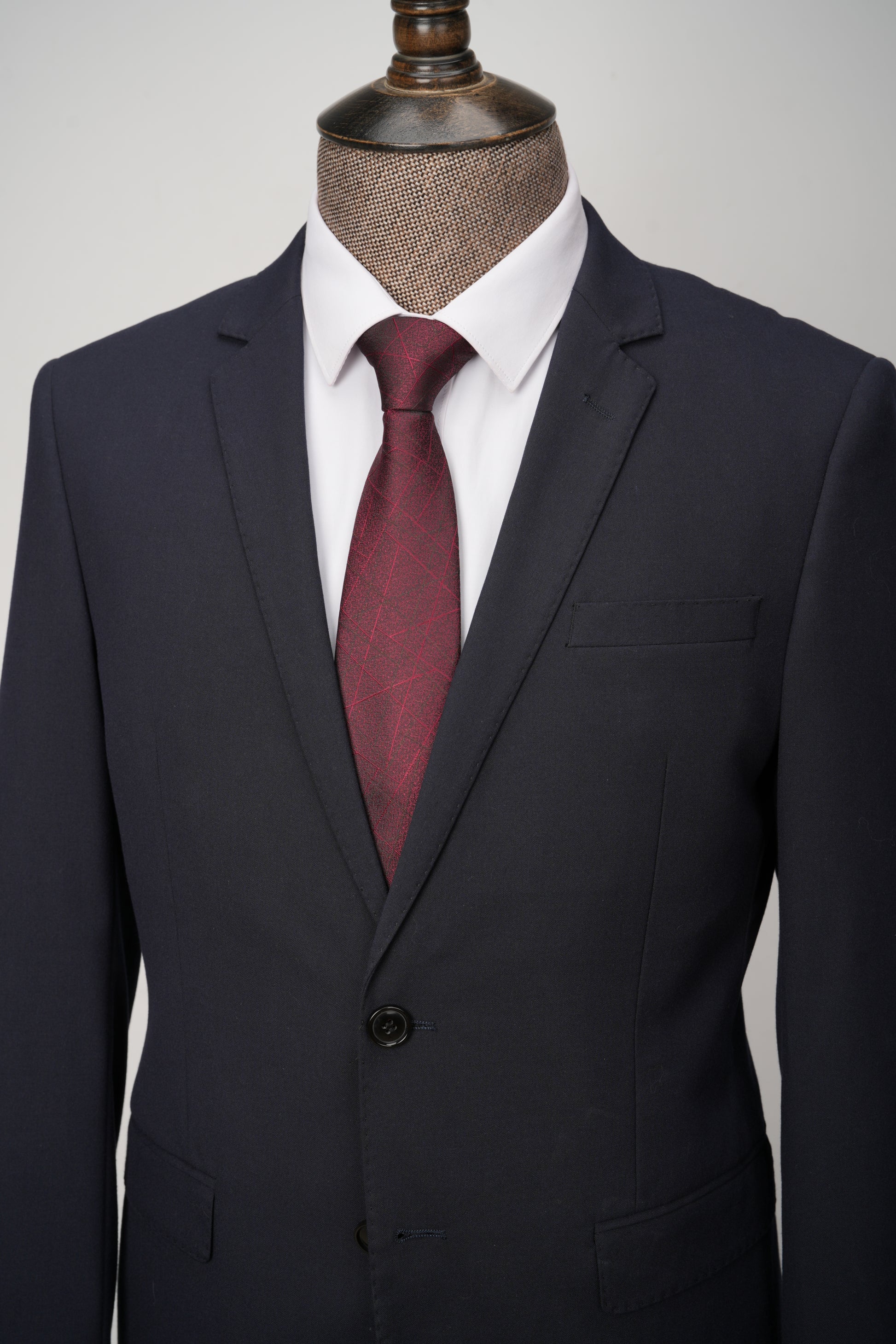 Black suit with a red tie on a mannequin against a gray background