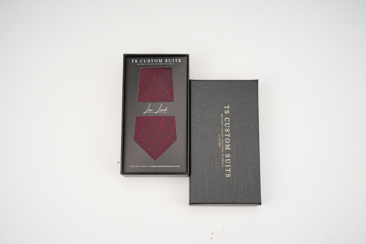 Maroon tie in a gray box with 'TS Custom Suits' branding on a white background