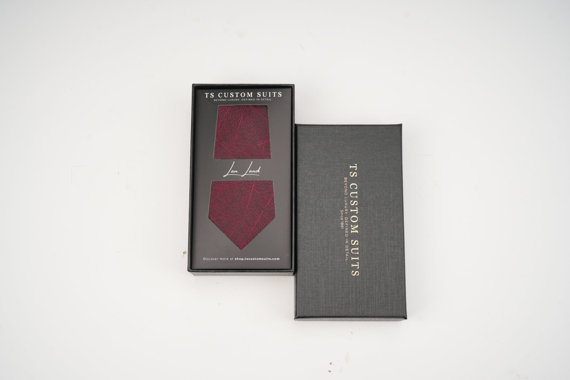 Maroon tie in a gray box with 'TS Custom Suits' branding on a white background