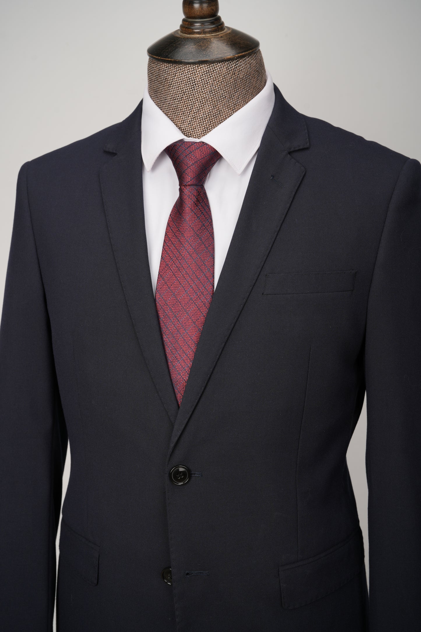 Black suit jacket with a red patterned tie on a mannequin against a gray background