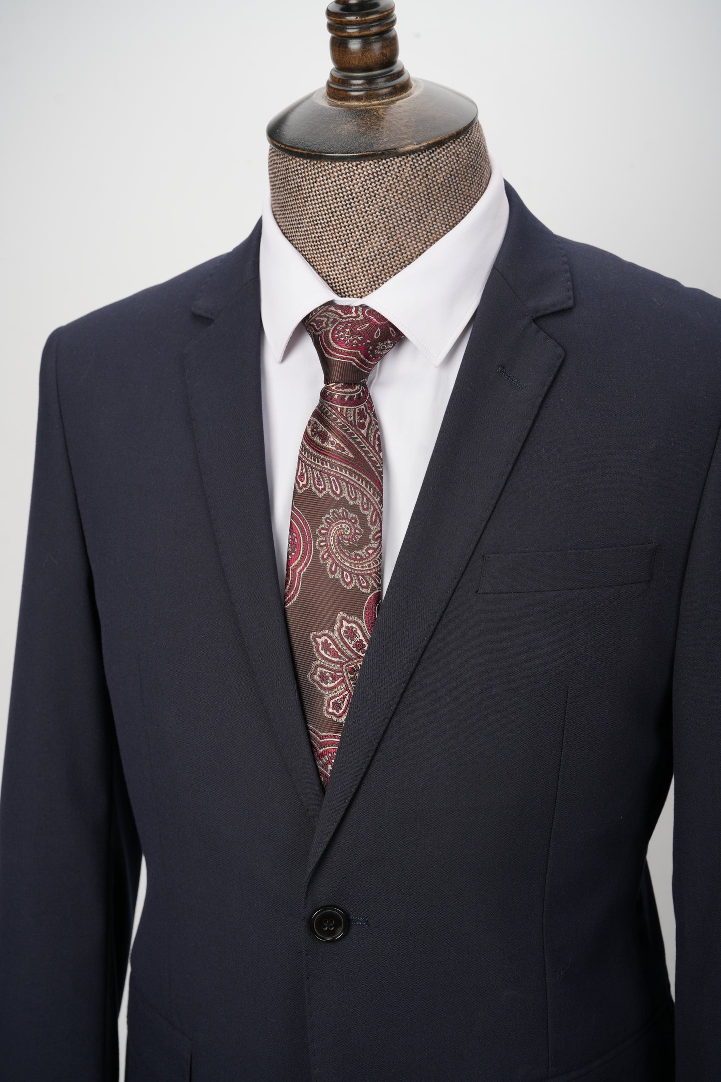 Dark suit with a patterned tie on a mannequin against a white background
