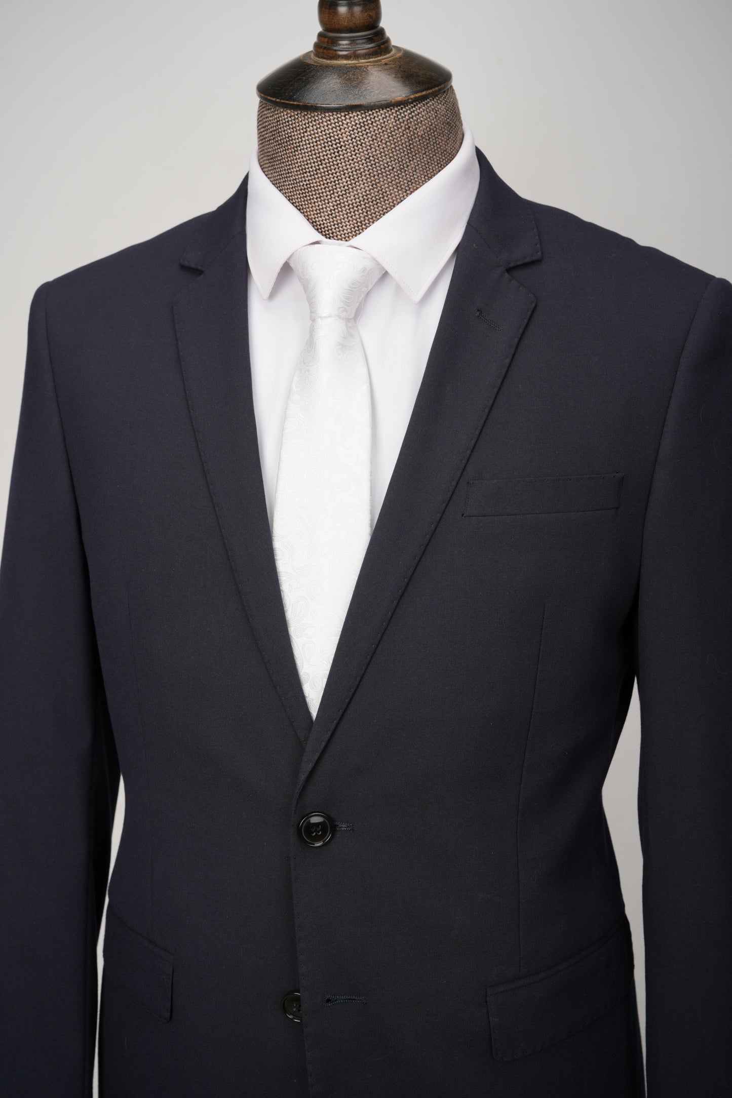 Black suit jacket on a mannequin with a white shirt against a gray background