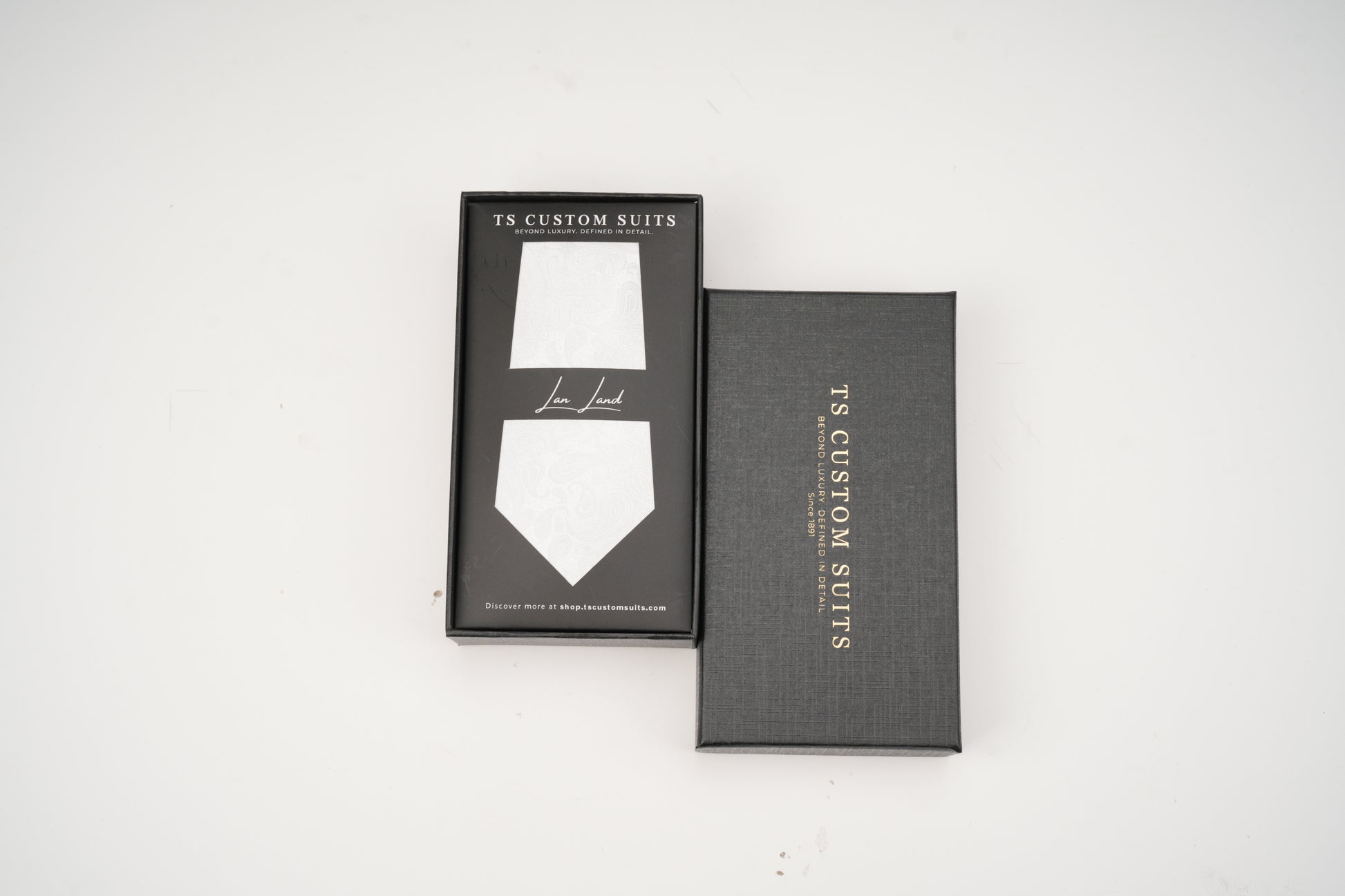 Gray box with a white tie design and 'TX Custom Suits' branding on a white background